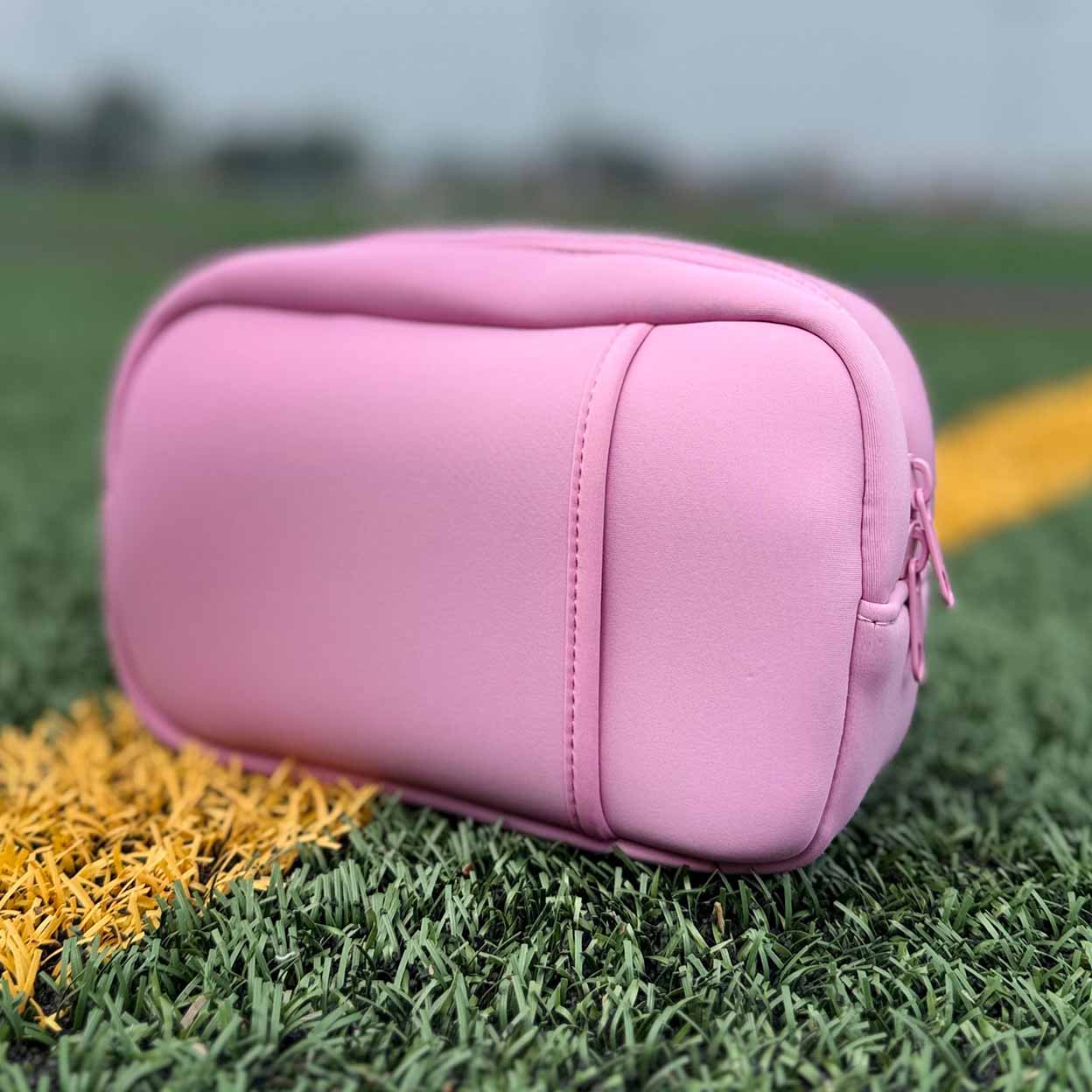 Pink pouch on artificial grass with a blurred background