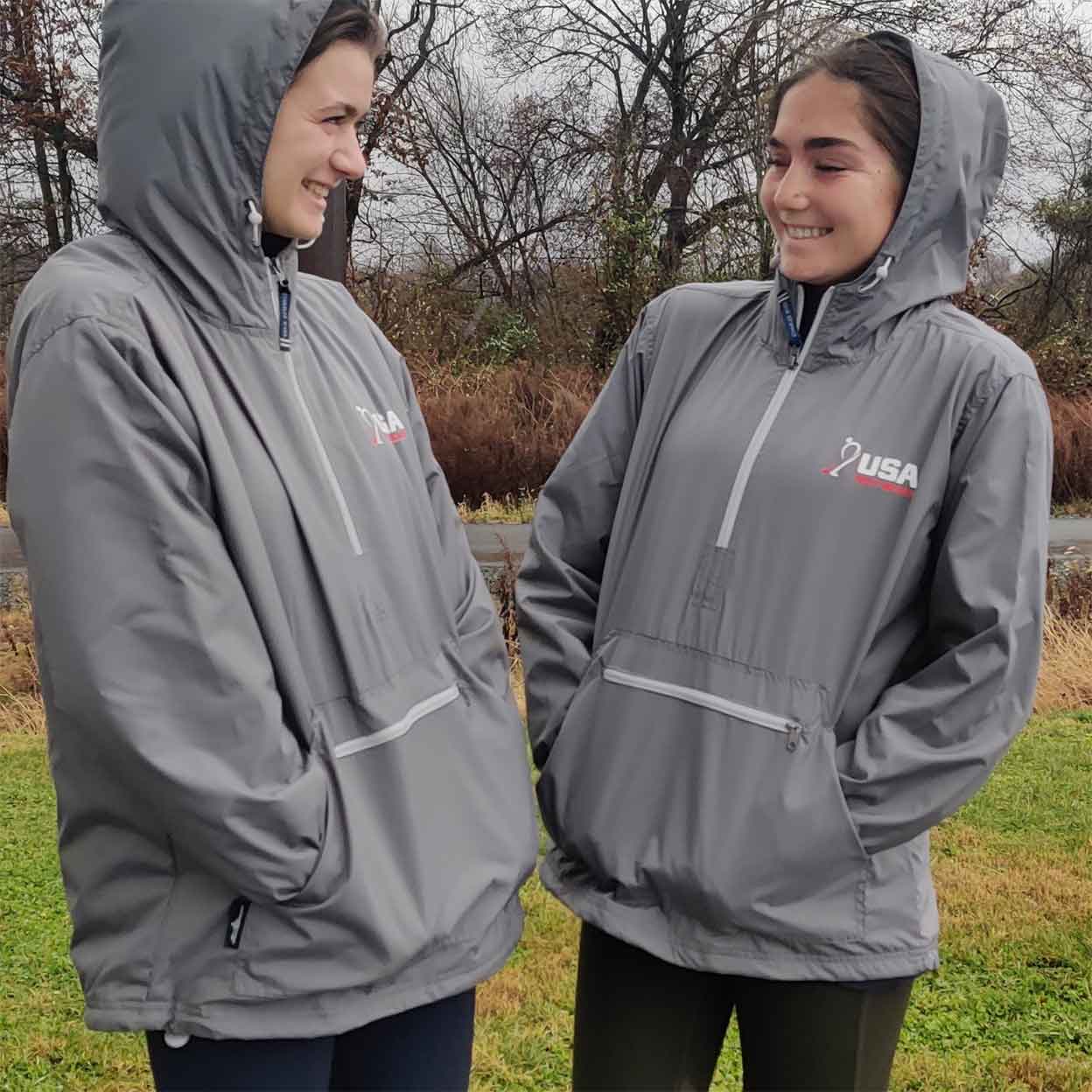 Two girls wearing the USA Field Hockey Unisex Anorak Jacket with their hoods up.