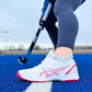 White and pink sports shoes on a blue field with a hockey stick in the background