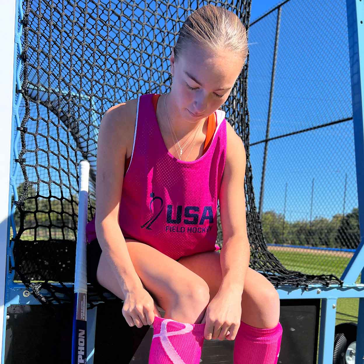 Field hockey player in a pink USA Field Hockey Ladies Mesh Reversible Pinnie.
