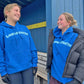 Two people wearing blue hoodies with Longstreth branding, standing in front of a blue wall.