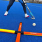Person playing field hockey on a blue turf with equipment and ball.