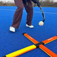 Person playing field hockey on a blue turf with a goal in the background