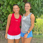 Two women in athletic wear standing outdoors with greenery in the background