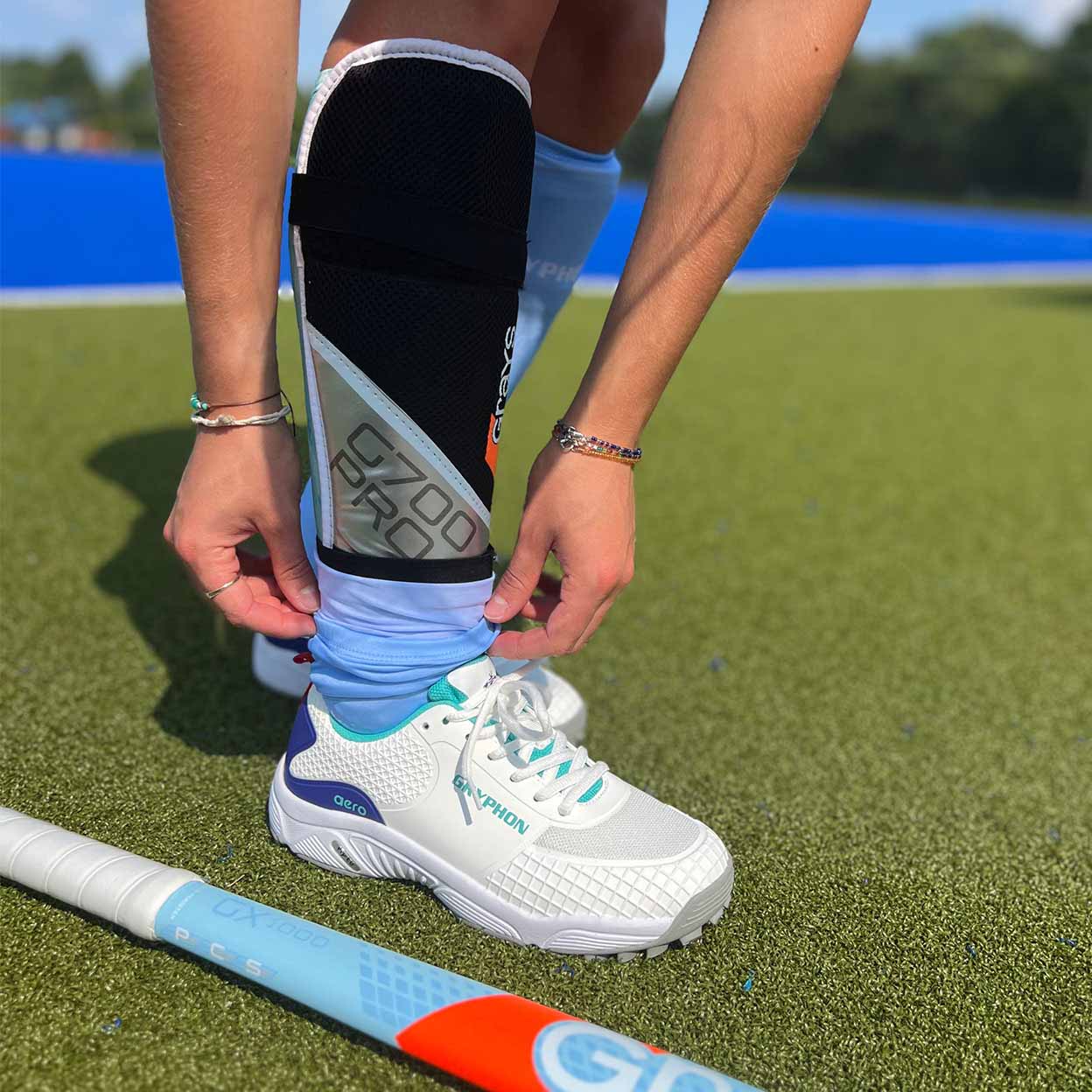 someone putting on the Grays G700 Pro Field Hockey Shinguards.