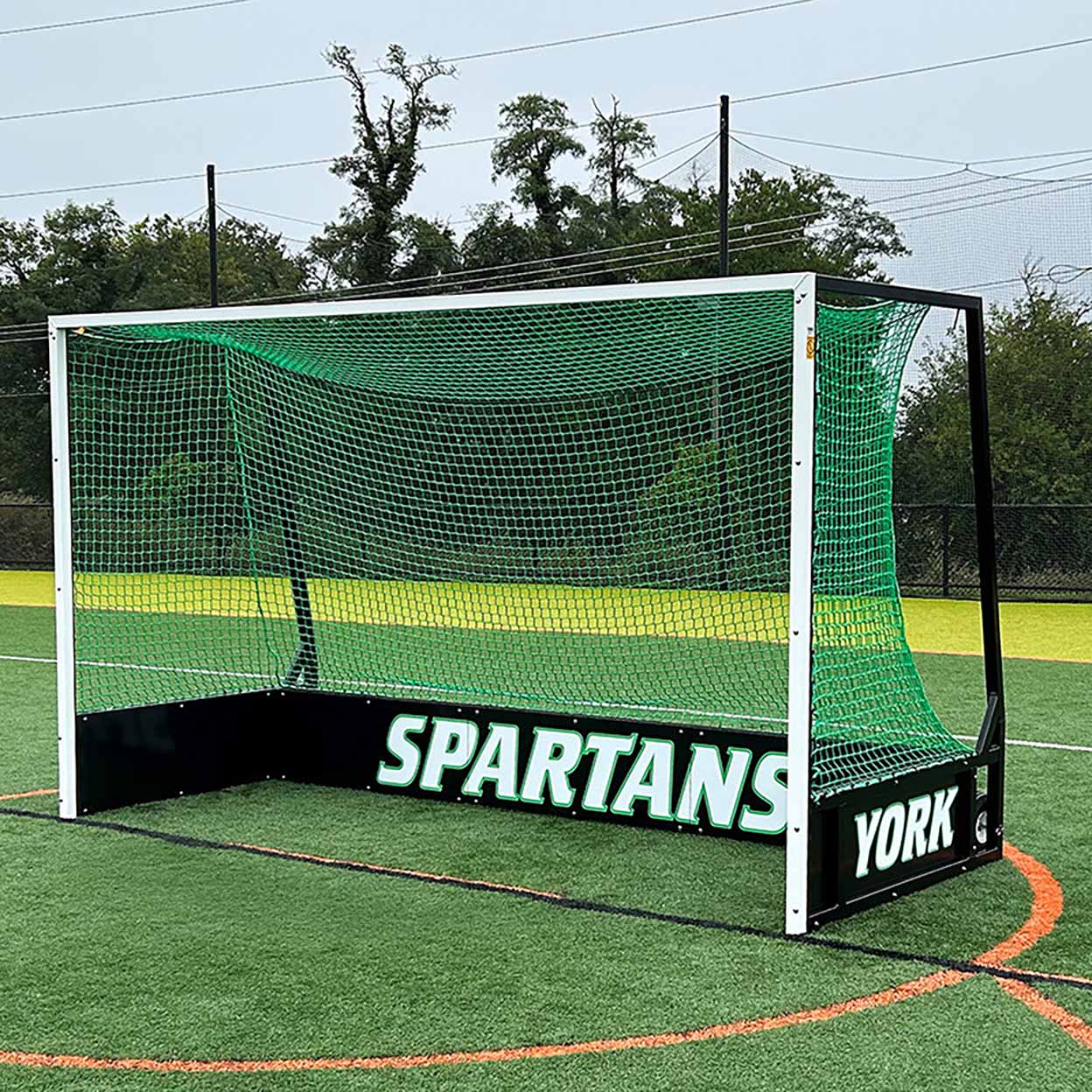 Spartans York field hockey goal on a sports field with trees in the background