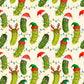 A repeating Christmas-themed pattern featuring cartoon green cucumbers with faces, some wearing Santa hats and elf hats, decorated with multicolored string lights on a cream background.