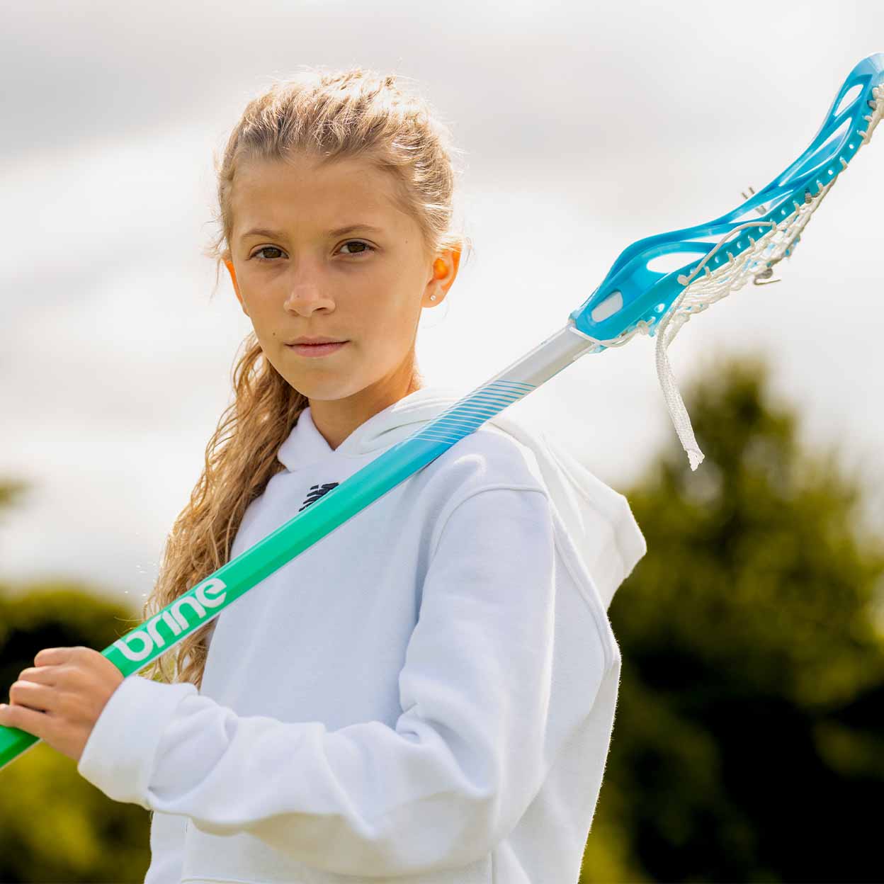 Girl holding the Brine Krown Rise Complete Lacrosse Stick over her shoulder.