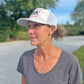 Woman wearing a white cap with 'USA' and 'Hockey' text, standing outdoors.