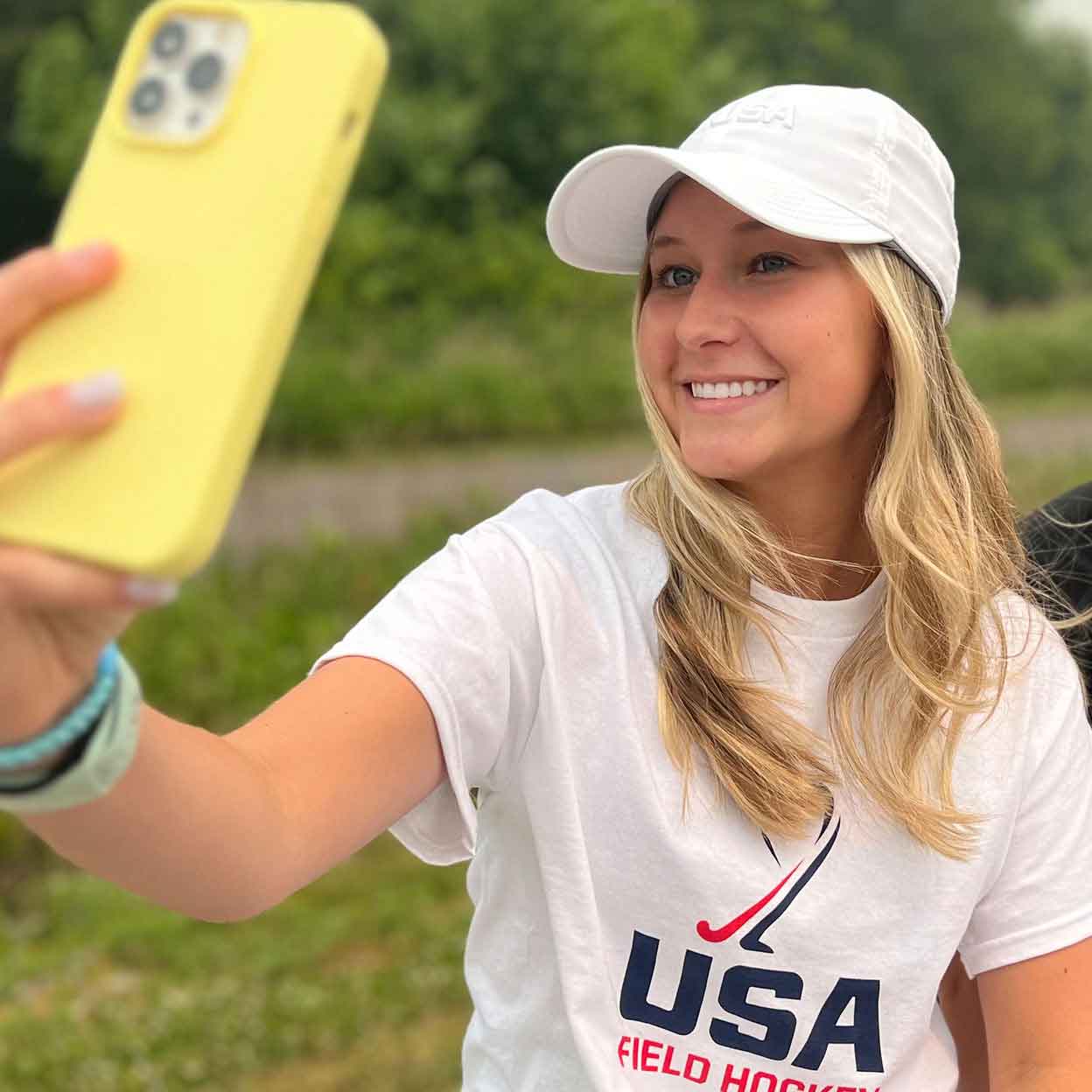 Smiling girl taking a selfie and wearing a USA field hockey hat