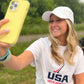 Smiling girl taking a selfie and wearing a USA field hockey hat