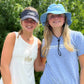 Two girls, one wearing a hat and the other wearing the USA Field Hockey Visor with Embroidered Logo.