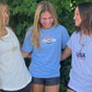 Laughing girl wearing the USA Field Hockey Reclaim Tee standing between two other girls.