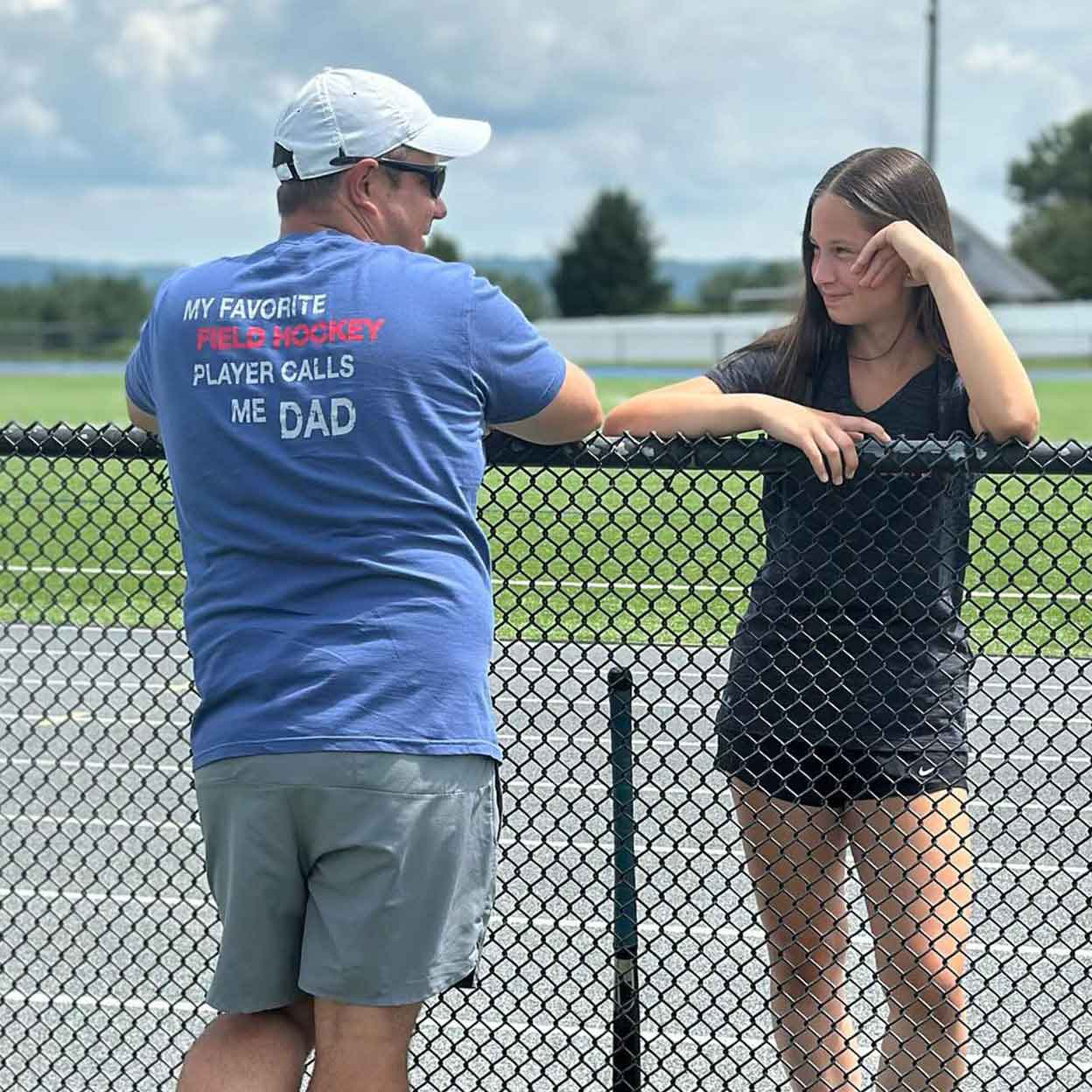 father in a Field Hockey Dad Pocket Tee with daughter hockey player.