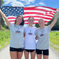 models wearing USA Field Hockey Under Armour Tee while holding a US flag