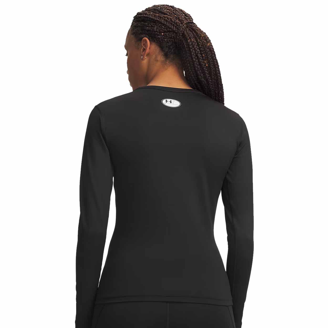 A woman shown from the back wearing a fitted black long-sleeve athletic top with a small white Under Armour logo centered below the neckline, against a plain white background.