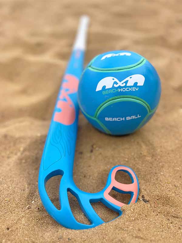 Blue and pink beach hockey stick and ball on sand