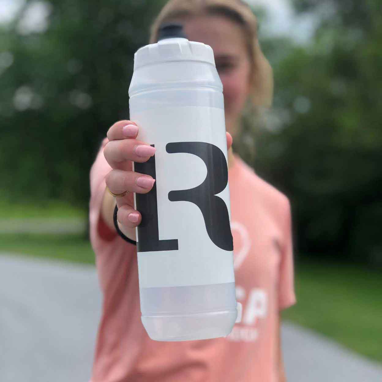 Girl holding the Ritual Bomber Water Bottle out in front of her.